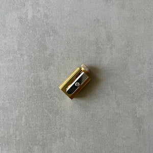 Gold-colored pencil sharpener on a gray surface