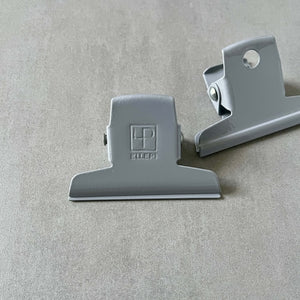 Two gray clips by Ellepi on a gray background
