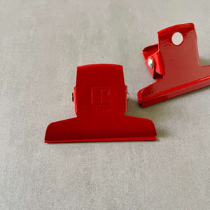 Two red clips by Ellepi on a gray background