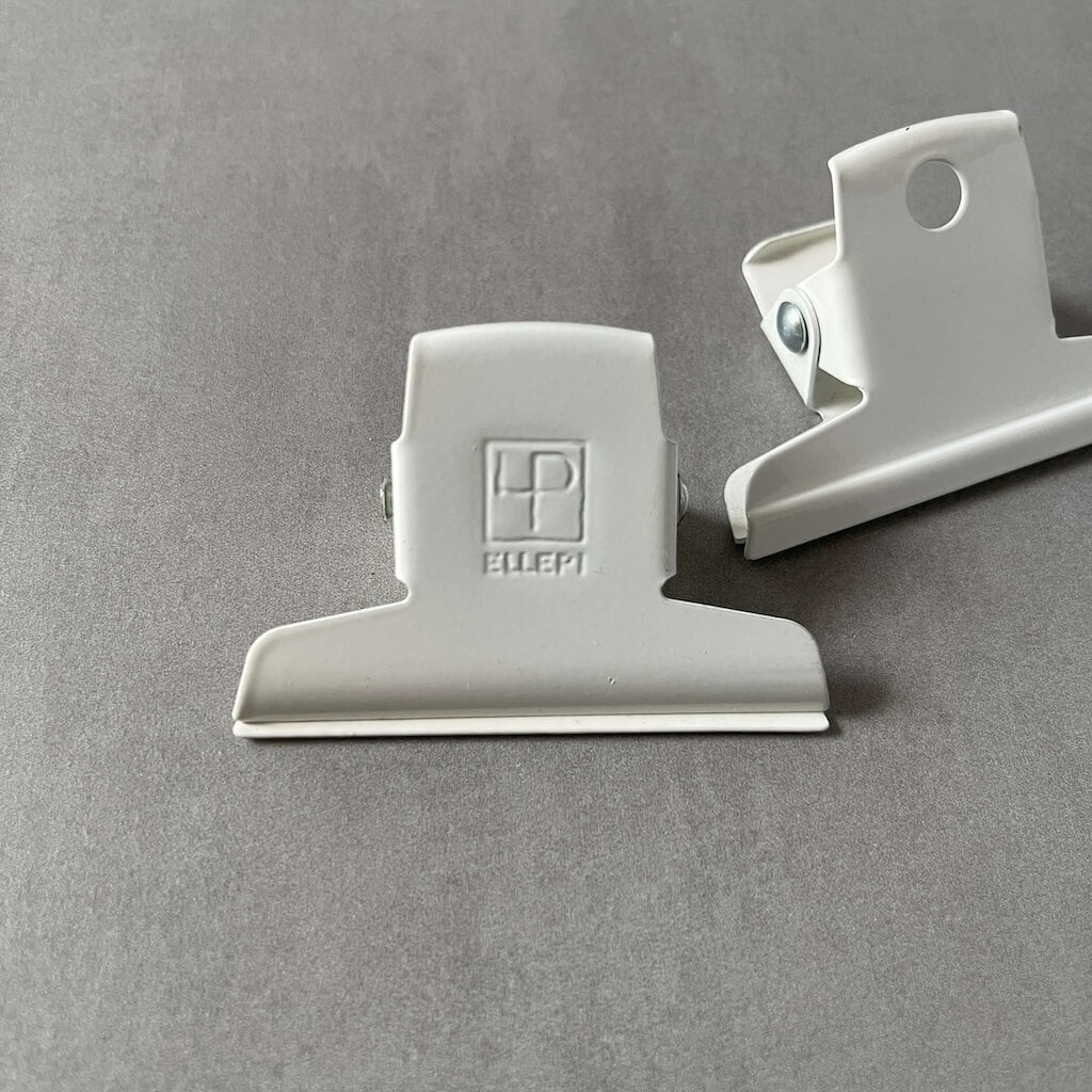 Two white clips by Ellepi on a gray background