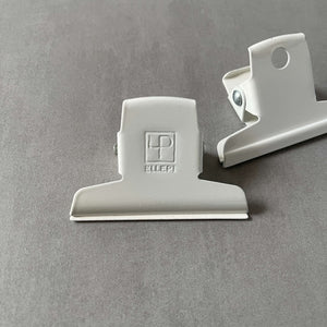 Two white clips by Ellepi on a gray background