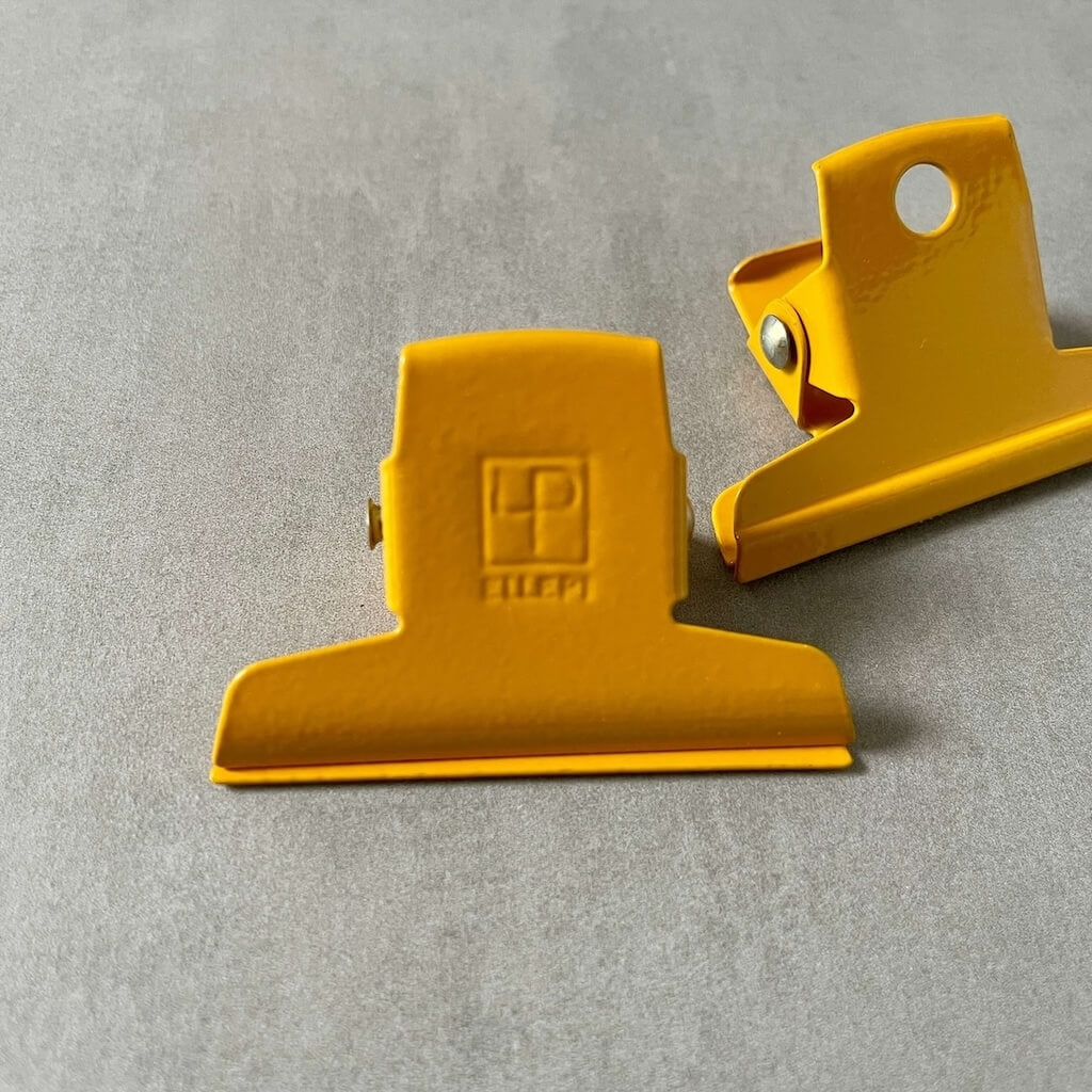 Two yellow clips by Ellepi on a gray background