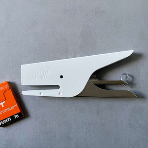 White stapler with a small box of staples on a gray background