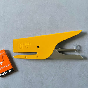 Yellow stapler with a small box of staples on a gray background