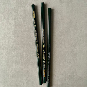 Three green pencils with visible gold 'Kita-Boshi' branding on a gray textured background