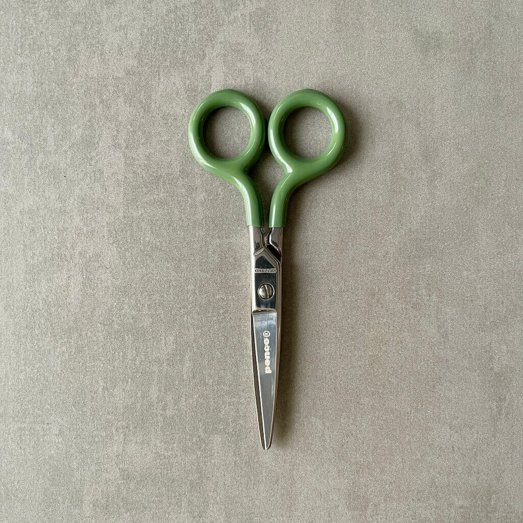 Four pairs of scissors with colored handles and 'Penco' brand on a gray background