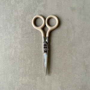 Pair of 'Penco' brand scissors with beige handles on a gray background