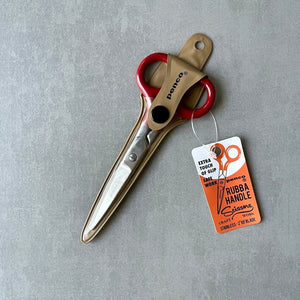 Pair of scissors with a 'Penco' brand tag in case on a gray background