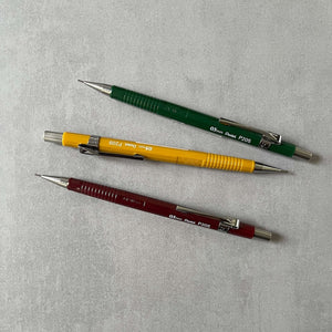 Three mechanical pencils in different colors on a gray background