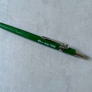 Green mechanical pencil with silver clip on a light gray background