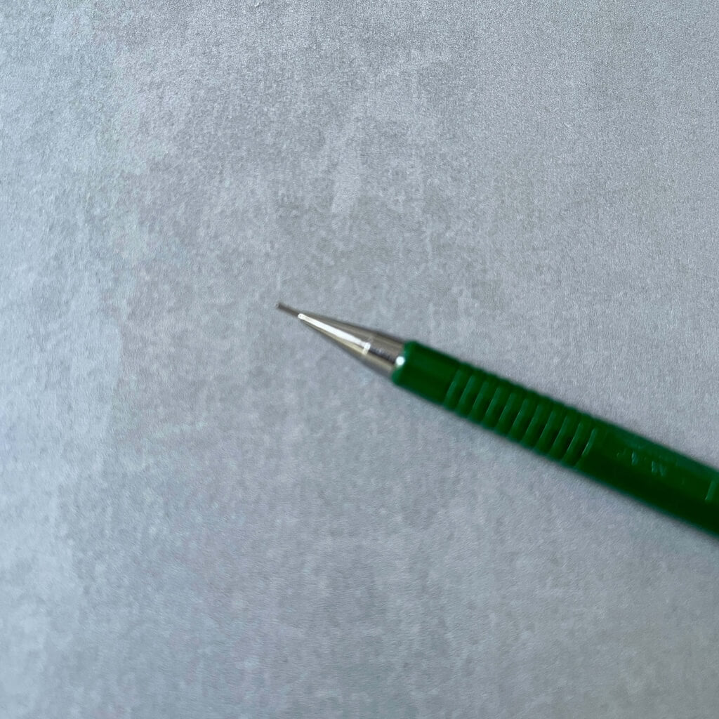Green pen with a metallic tip on a gray textured background