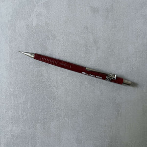 Red Pentel Sharp mechanical pencil on a gray textured background