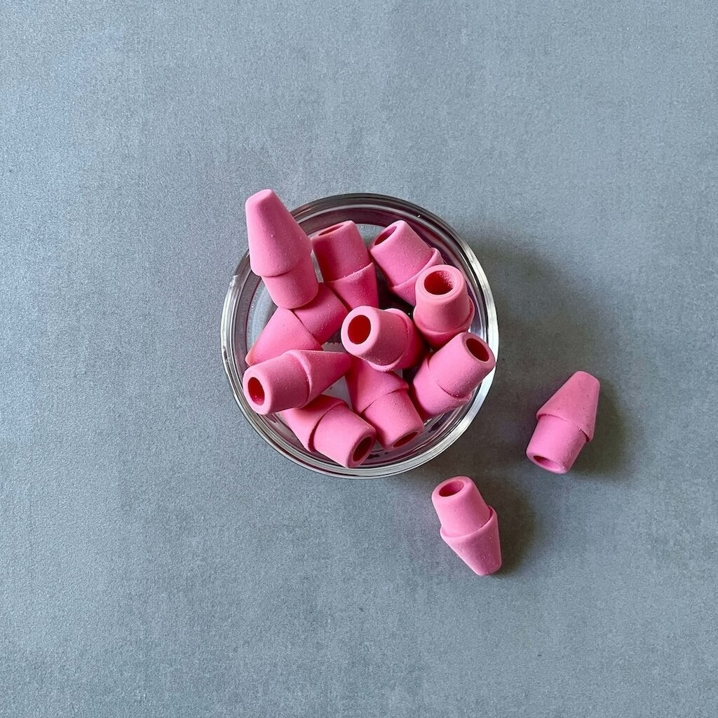 Pink rubber erasers in a clear container on a gray background