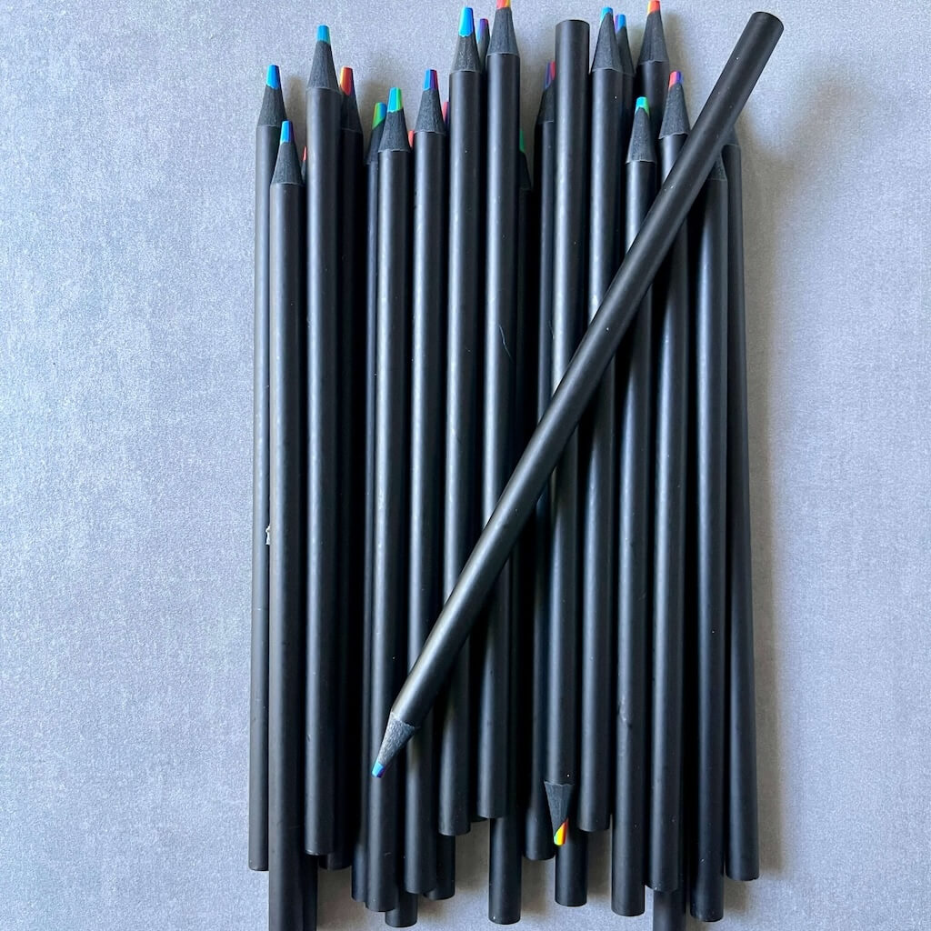 Set of black colored pencils with colorful tips on a gray background