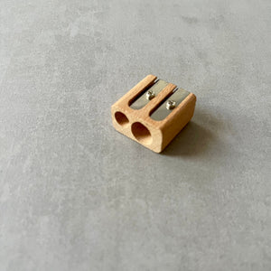 Wooden dual pencil sharpener on a gray surface