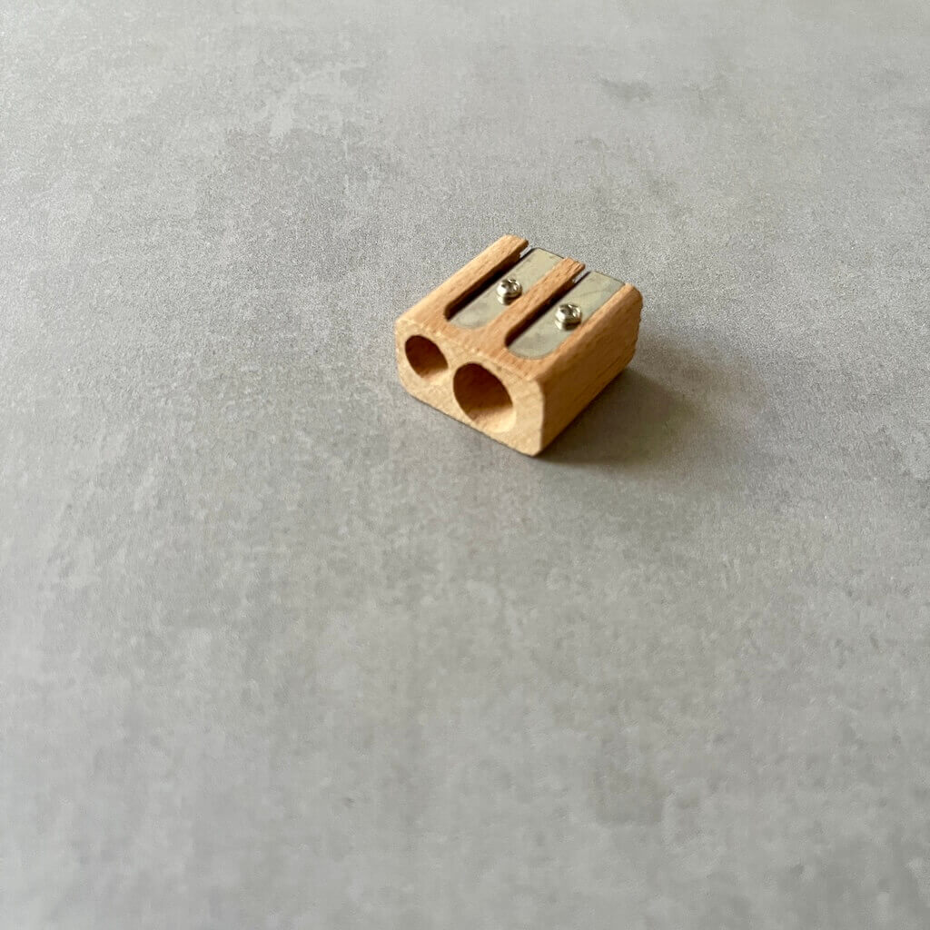 Wooden pencil sharpener with two openings on a gray surface.